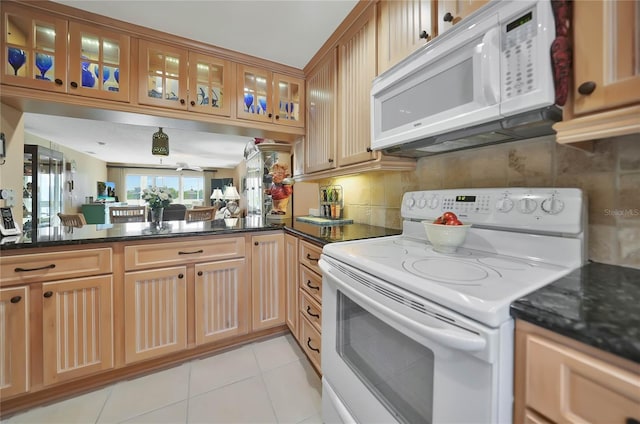 kitchen featuring white appliances, dark stone counters, tasteful backsplash, light tile patterned flooring, and kitchen peninsula