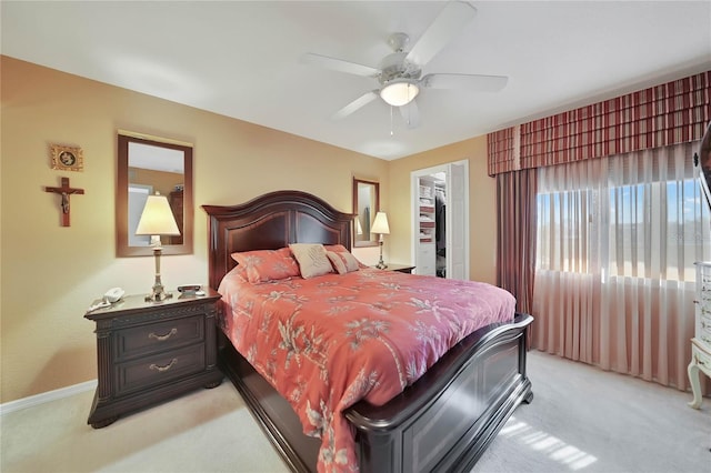 bedroom with a walk in closet, a closet, ceiling fan, and light colored carpet