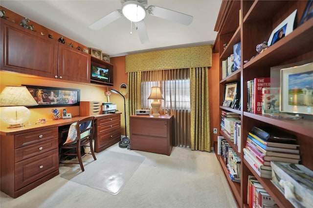 carpeted office space with ceiling fan and built in desk