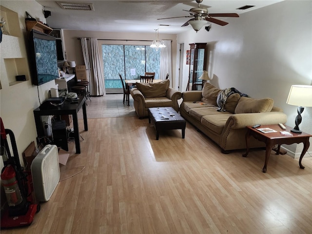 living room featuring ceiling fan with notable chandelier and light hardwood / wood-style flooring