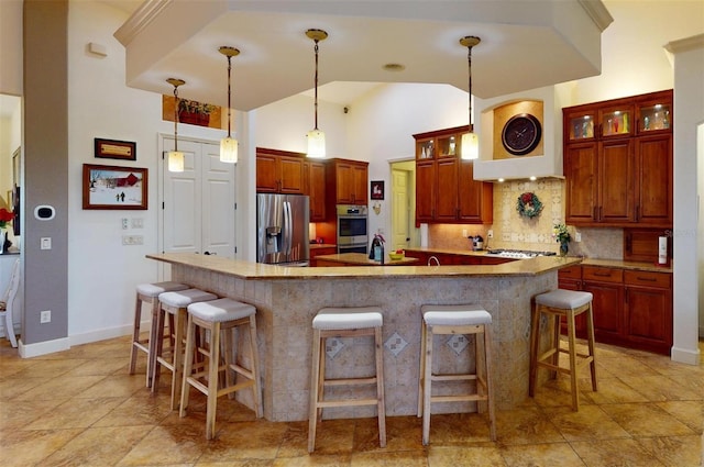 kitchen featuring pendant lighting, stainless steel appliances, high vaulted ceiling, and an island with sink