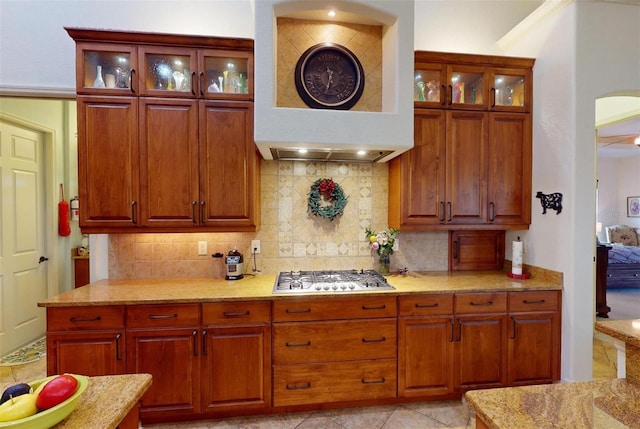 kitchen with decorative backsplash, light tile patterned floors, premium range hood, and stainless steel gas cooktop