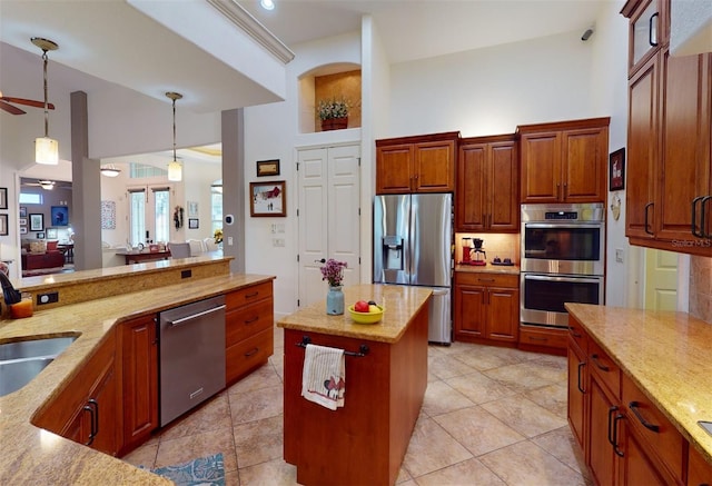 kitchen with sink, ceiling fan, decorative light fixtures, a kitchen island, and stainless steel appliances