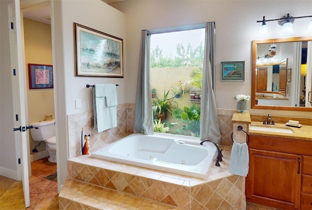 bathroom featuring tile patterned flooring, vanity, toilet, and tiled tub