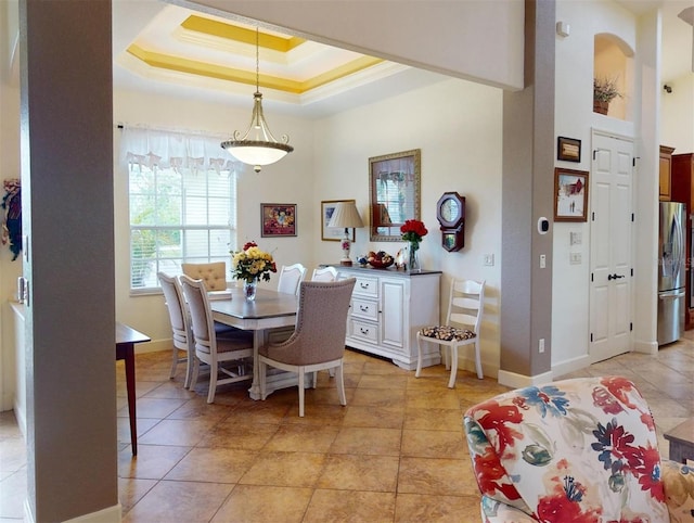 tiled dining area featuring crown molding and a tray ceiling