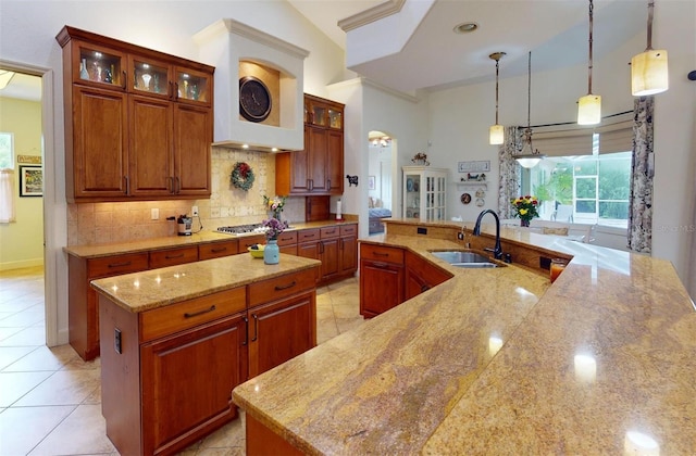 kitchen with sink, hanging light fixtures, light stone countertops, light tile patterned floors, and a large island