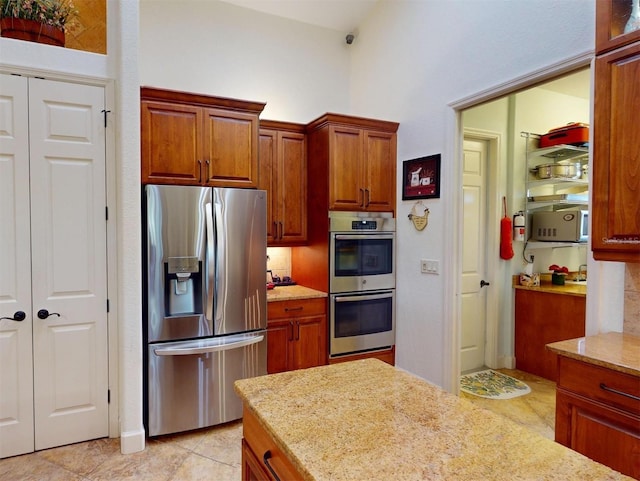 kitchen with light stone countertops, appliances with stainless steel finishes, and light tile patterned floors