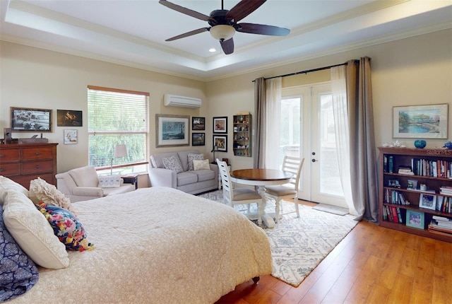 bedroom featuring access to exterior, a raised ceiling, a wall unit AC, ceiling fan, and light hardwood / wood-style floors