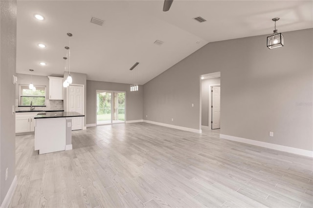 unfurnished living room with light wood-type flooring, lofted ceiling, and sink