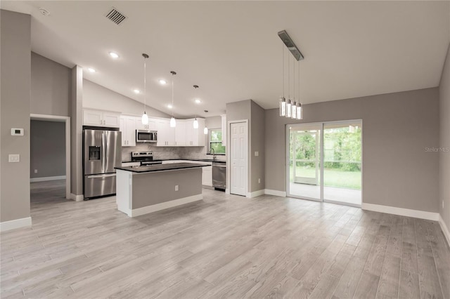 kitchen with a center island, white cabinets, stainless steel appliances, and decorative light fixtures