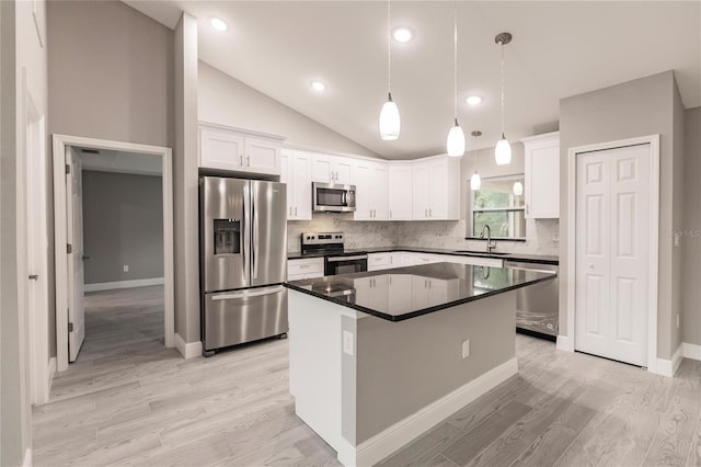 kitchen featuring appliances with stainless steel finishes, vaulted ceiling, sink, white cabinets, and a center island