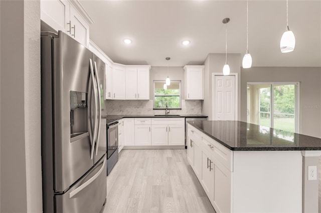 kitchen with stainless steel appliances, sink, white cabinets, a center island, and hanging light fixtures