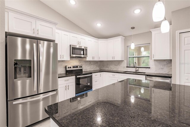 kitchen with sink, hanging light fixtures, appliances with stainless steel finishes, and vaulted ceiling