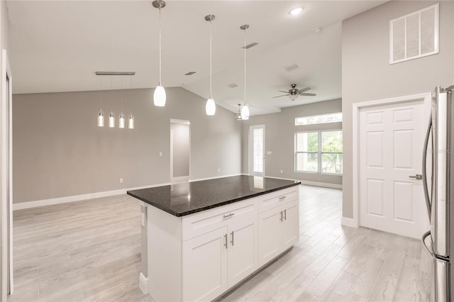 kitchen with a center island, hanging light fixtures, ceiling fan, white cabinetry, and stainless steel refrigerator