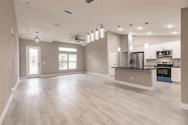 kitchen featuring white cabinets, a center island, stainless steel appliances, and hanging light fixtures