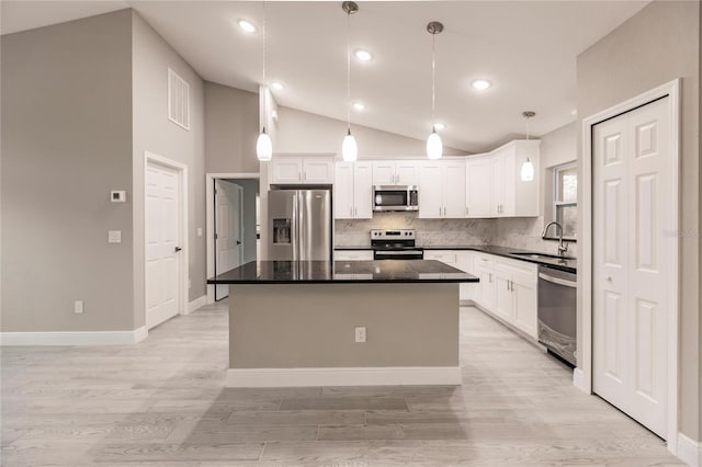 kitchen with pendant lighting, white cabinets, sink, appliances with stainless steel finishes, and a kitchen island