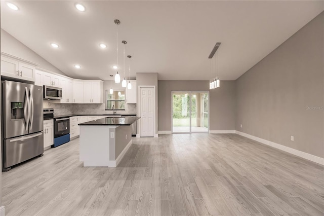 kitchen featuring white cabinetry, a kitchen island, decorative light fixtures, and appliances with stainless steel finishes