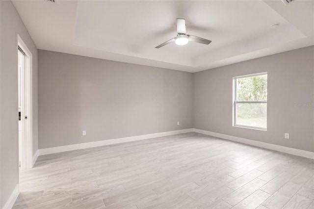 spare room featuring light hardwood / wood-style flooring, a raised ceiling, and ceiling fan