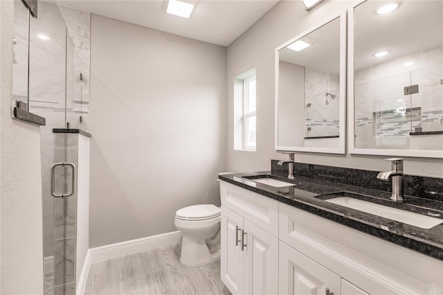 bathroom featuring hardwood / wood-style floors, vanity, a shower with shower door, and toilet