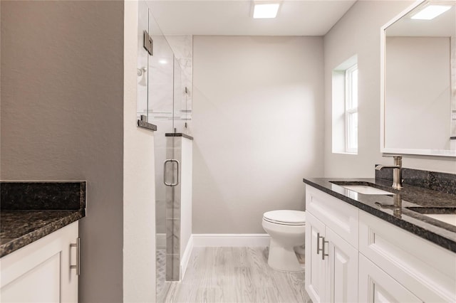 bathroom featuring hardwood / wood-style flooring, a shower with door, vanity, and toilet