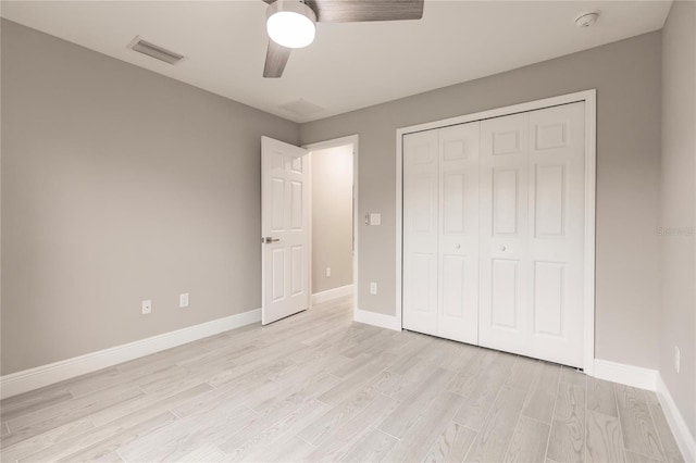 unfurnished bedroom with ceiling fan, light wood-type flooring, and a closet