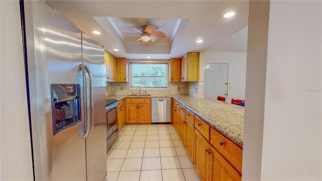 kitchen featuring ceiling fan, stainless steel appliances, a raised ceiling, tasteful backsplash, and kitchen peninsula