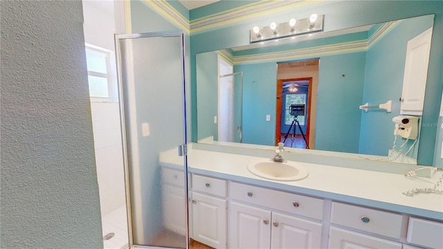 bathroom with vanity, a shower with shower door, and ornamental molding