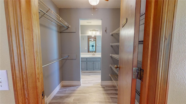 walk in closet featuring ceiling fan, light wood-type flooring, and sink