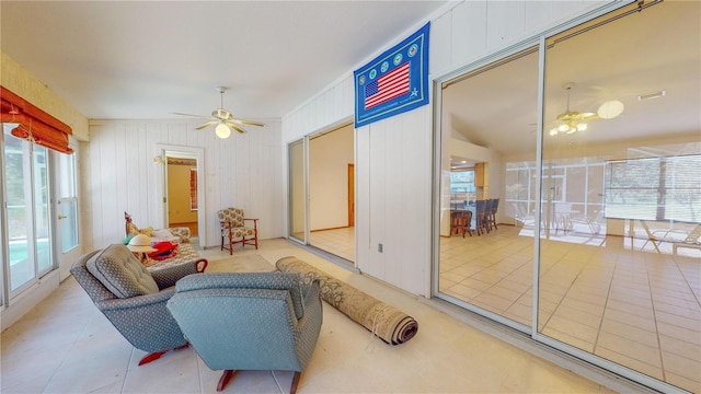 tiled living room with ceiling fan, wood walls, and vaulted ceiling