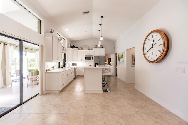 kitchen featuring a center island, hanging light fixtures, light tile patterned floors, white cabinetry, and stainless steel refrigerator