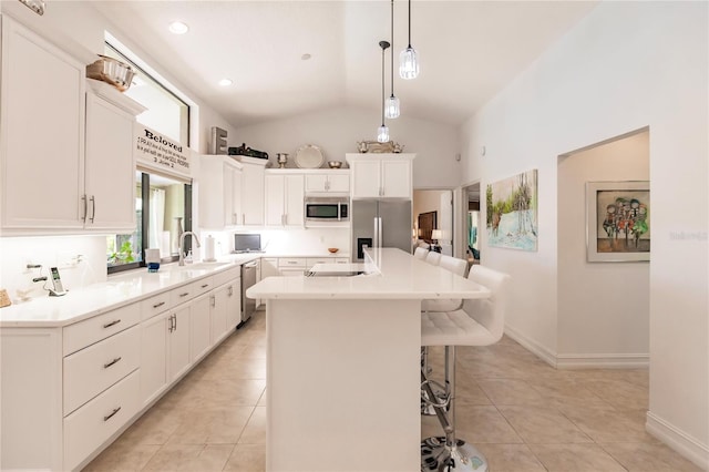 kitchen with a kitchen bar, stainless steel appliances, vaulted ceiling, and a kitchen island with sink