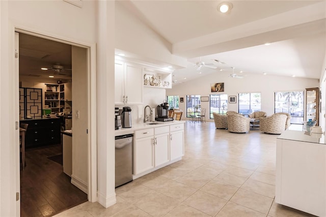 kitchen with sink, white cabinets, stainless steel dishwasher, and vaulted ceiling