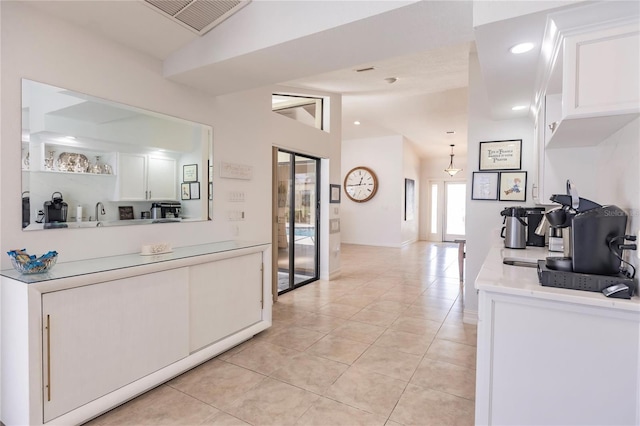 interior space with light tile patterned floors, white cabinets, and vaulted ceiling