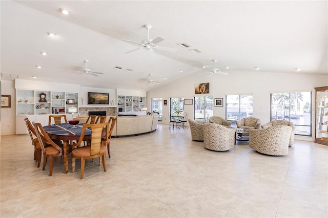 tiled dining area featuring a fireplace, ceiling fan, and lofted ceiling