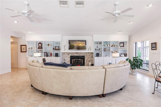 living room with light tile patterned floors, ceiling fan, lofted ceiling, and a tiled fireplace