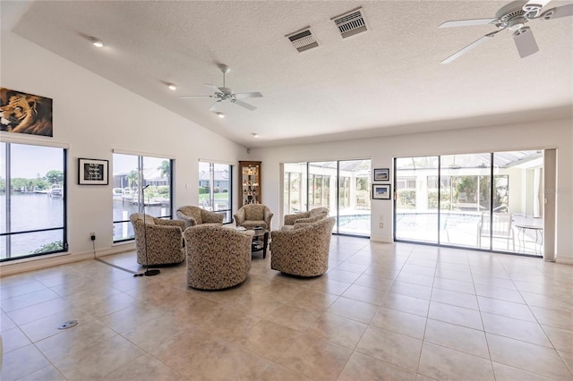 living room featuring light tile patterned floors, a textured ceiling, a water view, and ceiling fan