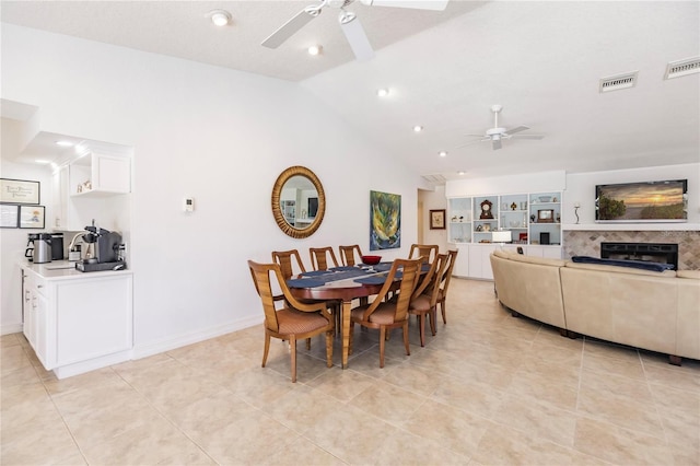 dining room featuring a fireplace, ceiling fan, lofted ceiling, and light tile patterned flooring