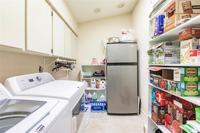 clothes washing area with washer and dryer, light tile patterned floors, and cabinets