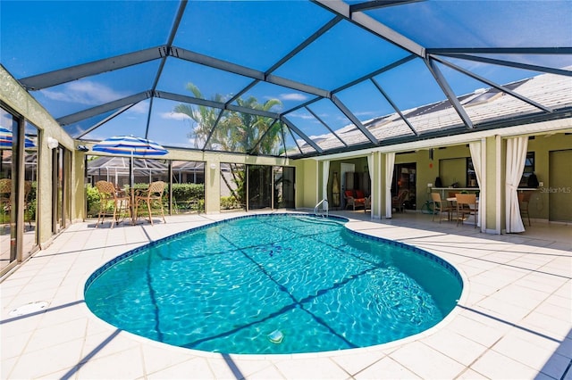 view of pool with glass enclosure and a patio area