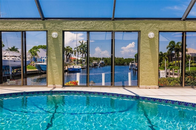 view of swimming pool with a lanai, a water view, and a patio