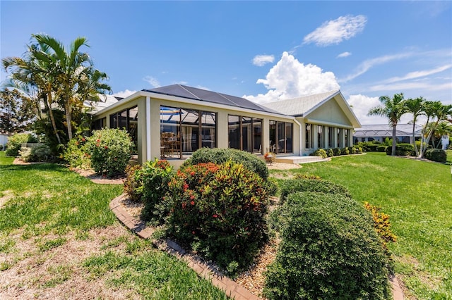 rear view of house with a lawn and a sunroom