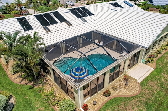 rear view of property with a lanai and solar panels