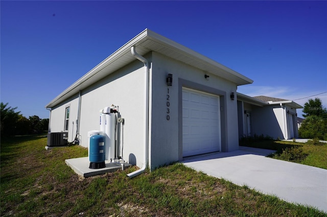 view of side of home featuring a garage, cooling unit, and a yard