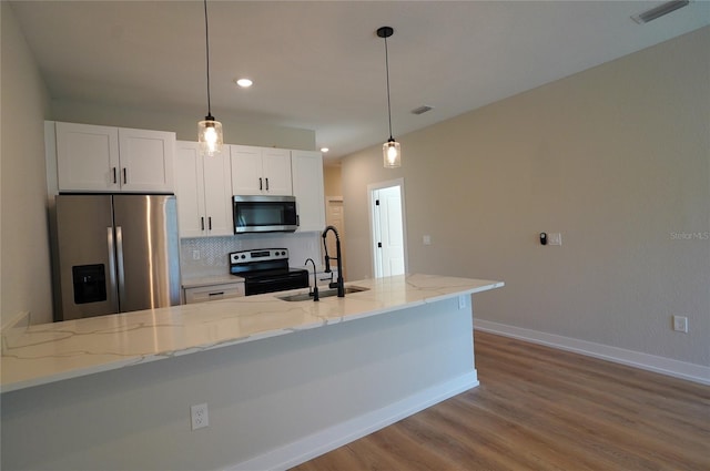 kitchen with appliances with stainless steel finishes, decorative light fixtures, light stone countertops, white cabinets, and sink