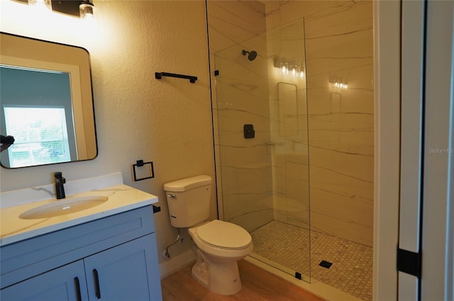 bathroom with hardwood / wood-style flooring, an enclosed shower, vanity, and toilet