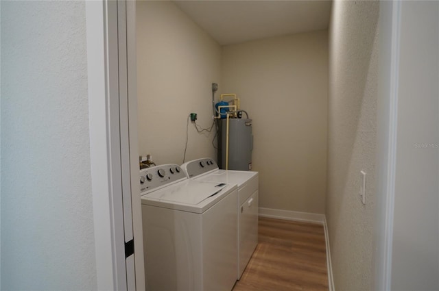 clothes washing area featuring light wood-type flooring, separate washer and dryer, and electric water heater