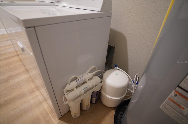 bathroom with washing machine and dryer, water heater, and wood-type flooring