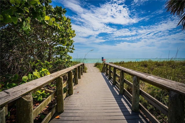 view of dock featuring a water view and a beach view