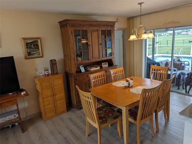 dining space with light hardwood / wood-style floors and a notable chandelier