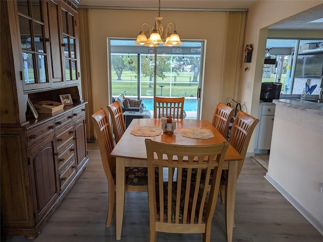 dining area with a wealth of natural light, a notable chandelier, and hardwood / wood-style flooring